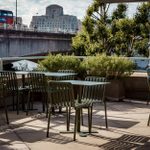 Green metal tables and chairs set out on the outside terrace of Forza Wine, looking towards Waterloo Bridge.
