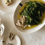 A dish of oysters and one of a cooked fish dressed with greens