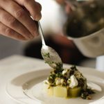 LASDUN restaurant a dish of Norfolk Leeks, Goat’s Curd & Hazelnut being plated up, sauce being added by spoon from a small steel saucepan