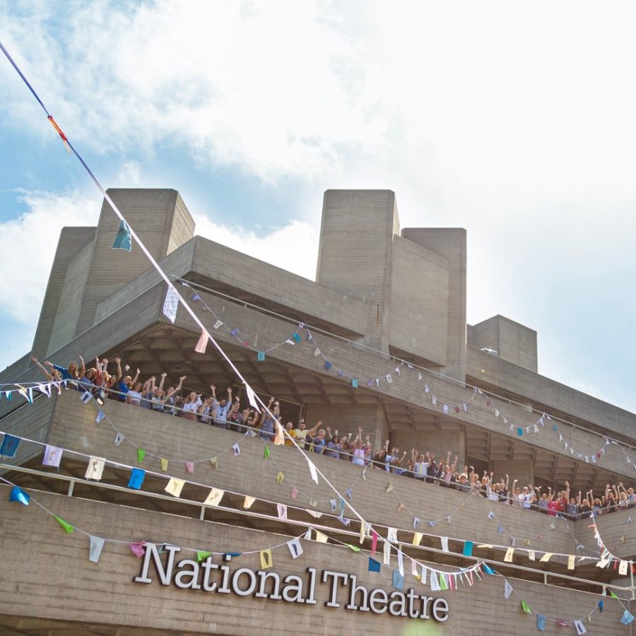 The National Theatre building with crowds waving on the upper terrace and bunting hung on three terraces